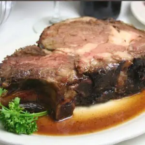 a slice of smoked prime rib roast on a plate with sauce